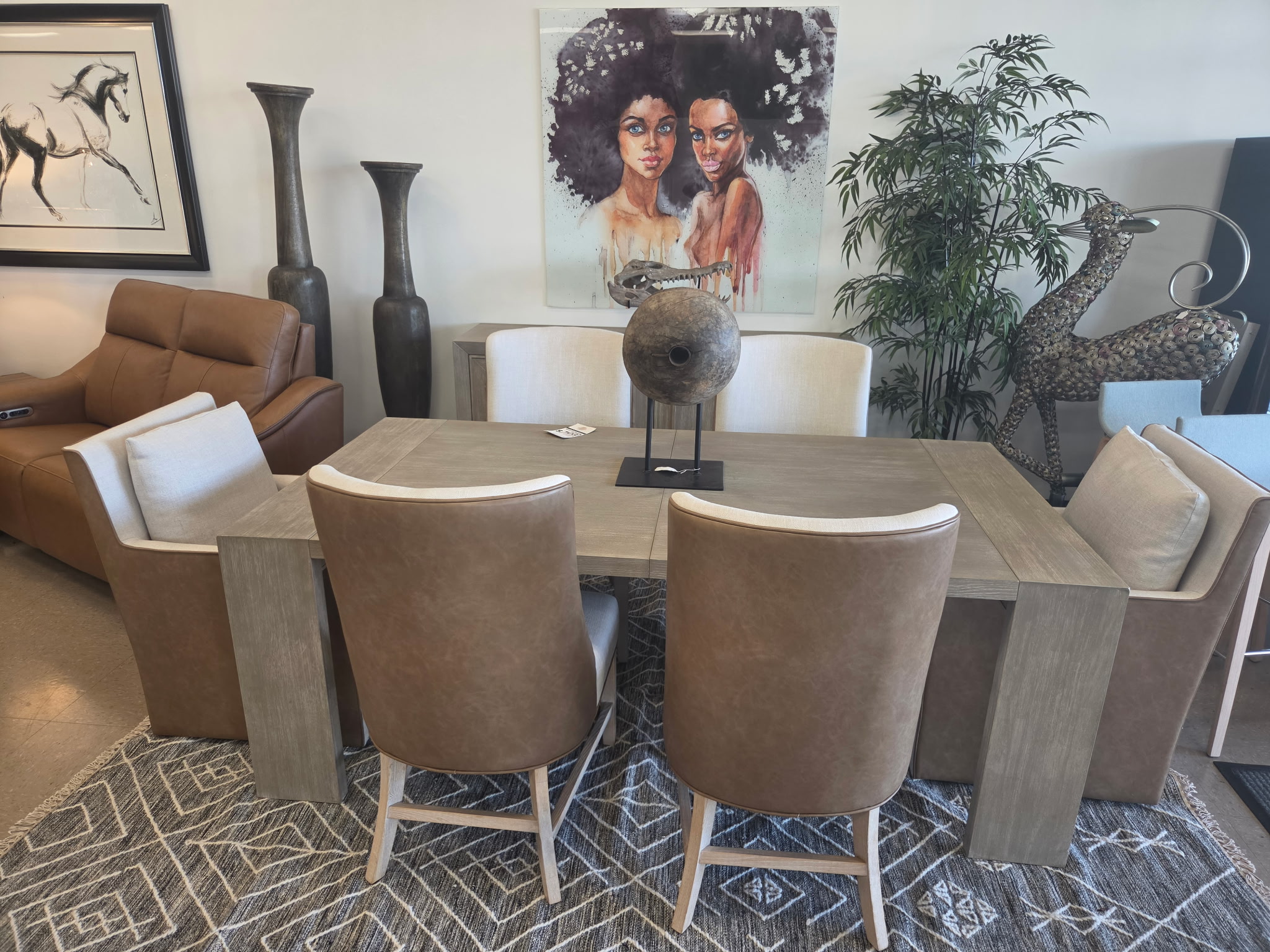 Dining table with leather and upholstered chairs and wall art